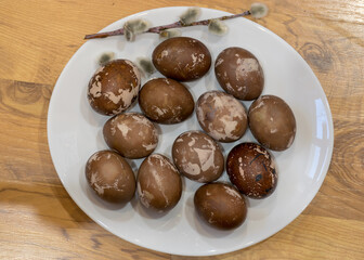 Easter eggs on a plate, European Easter with traditional decoration eggs, easter eggs decorated with natural fresh leaves and boiled in onions peels and blueberry berries