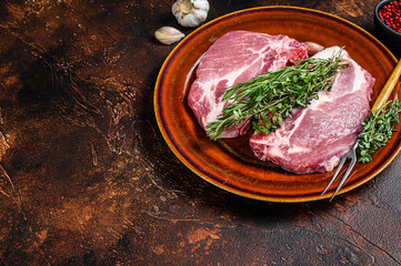 Fresh Raw pork loin steaks from neck meat. Dark background. Top view. Copy space
