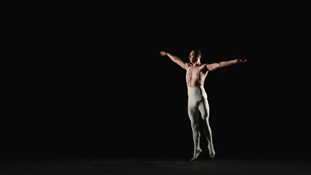 Male ballet dancer performs acrobatic element on a black background. Slow motion