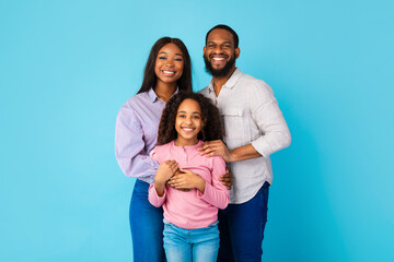 African American man and woman hugging smiling daughter