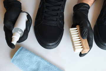 Man is cleaning sneakers in a workshop. Shoe shine service. The shoemaker prepares the shoes for...