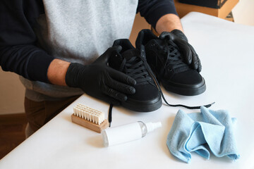Man is cleaning sneakers in a workshop. Shoe shine service. The shoemaker prepares the shoes for the season. Shoe brush close-up. Shoe care with a special product