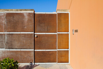 elegant wooden fence with door in orange wall and blue sky in the background