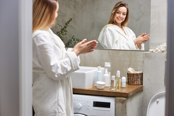 Good-looking woman use skin care products at home in light bathroom