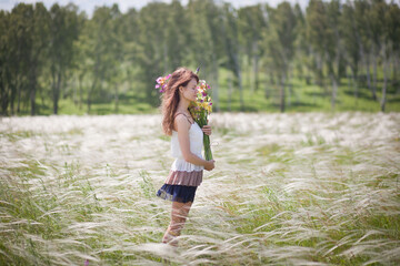 Obraz premium beautiful girl in a short dress walks across the field with a bouquet of irises in her hands, summer photo session, girl on vacation