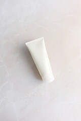 empty white cosmetic tube on a light pink marble background. Minimalistic cosmetic product concept, mock up, vertical