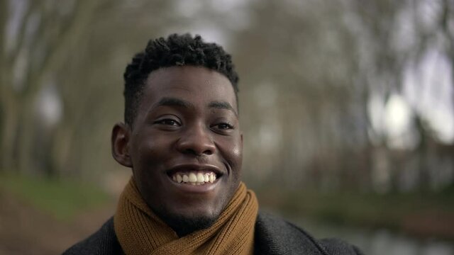 Happy young black man walking outside during winter feeling satsifaction and wellbeing