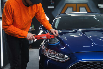 Man in a mask polishes car