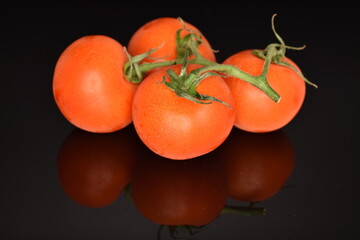 Several ripe organic, juicy, tasty smoothie tomato, macro, bright red, on a black background.