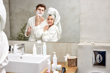 20-26 adults couple have fun, enjoy brushing teeth and do other morning procedures in bathroom