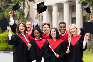 Joyful multiethnic students with diplomas celebrating graduation