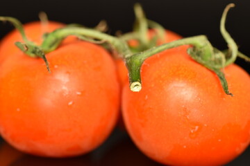 Several ripe organic, juicy, tasty smoothie tomato, macro, bright red, on a black background.