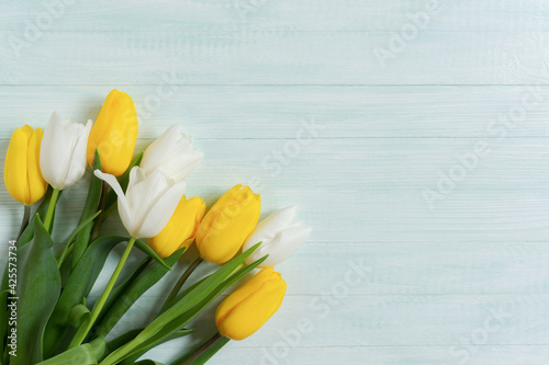 Yellow white tulips wooden mint background. Mock up for Birthday, Wedding, Mother's Day, International Women's Day. Flat lay, top view of a gift bouquet of tulips. Spring flower background, copy space