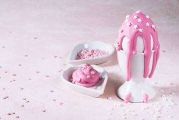 Easter egg in egg holder with pink icing and stars on pink concrete background