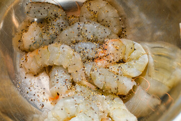 Fresh shrimp marinated with salt and pepper in a silver marinated bowl.