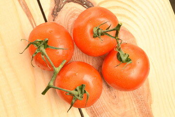 Several ripe, bright red, organic, delicious cocktail tomatoes, close-up, on a table made of natural wood.