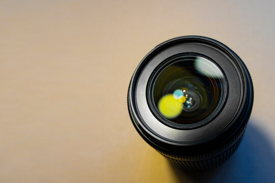 Wide angle camera lens with green flare reflaction on a wooden background..