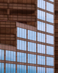 Geometric architectural abstract of reflective blue windows against brown wall of a contemporary office building