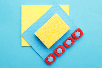 capsules for dishwashers, kitchen rags and sponges on a blue background. flat lay