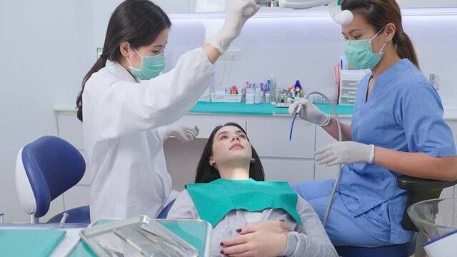 Asian female dental team performing tooth checkup for oral treatment.