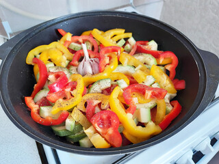 Chopped vegetables in a cast iron saucepan, tomatoes, bell peppers, potatoes, garlic, zucchini