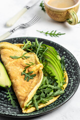 Omelette with avocado and arugula on plate. Frittata - italian omelet. Delicious vegan, vegetarian breakfast, vertical image Top view