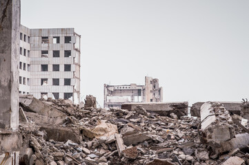 A pile of construction debris and large concrete fragments against the background of a destroyed...