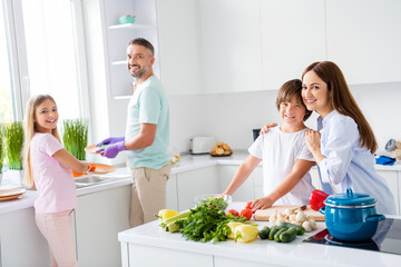 Photo portrait lovely couple with daughter and son cooking dishes on kitchen cutting vegetables for salad washing dishes together