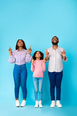 Fototapeta premium Smiling black family pointing up at free copy space