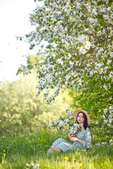 beautiful girl in a light dress and hat walks in the apple orchard, sakura blossom, walk in the fresh air, summer vacation