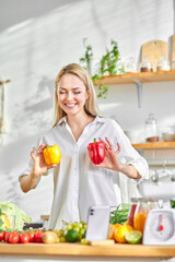 Happy caucasian female have fun in kitchen, with fresh organic vegetarian food on table