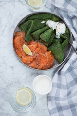 Green crepes with spinach and salmon carpaccio over light-grey marble background, vertical shot,...