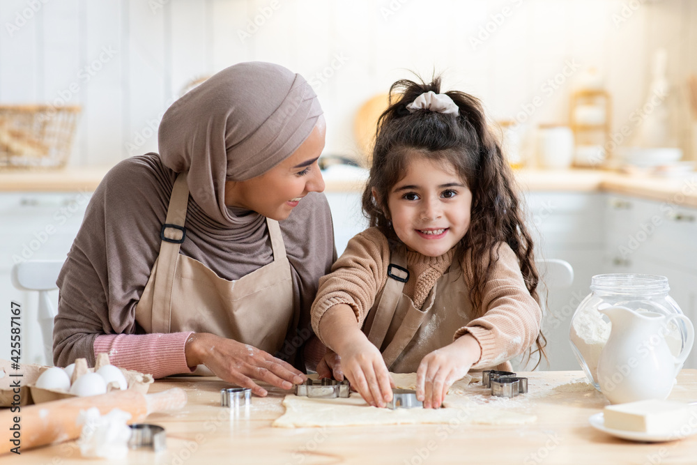 Wall mural Adorable Little Arab Girl Having Fun While Baking With Mother In Kitchen