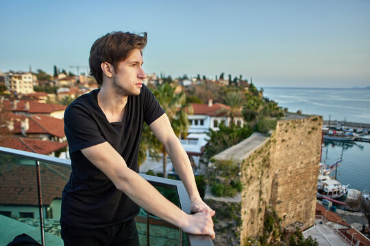 Early spring in Antalya, young white man looks at sea from observation deck above old city.