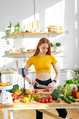 Healthy Food - Vegetable Salad. Young redhead woman preparing vegetable salad in the kitchen