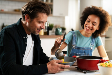 Boyfriend and girlfriend eating lunch together at home. Husband and wife enjoying in delicious food..