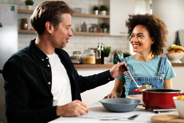 Boyfriend and girlfriend eating lunch together at home. Husband and wife enjoying in delicious food..