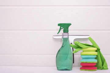 cleaning the house: colored rags, green gloves, detergent and a window brush