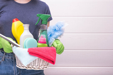woman holding a basket with detergents, brushes and rags for cleaning the house, close-up