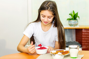 A pretty girl is sitting at home at the table at the morning breakfast. 