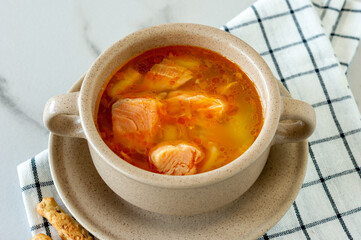 homemade soup with salmon with bread sticks on marble background.