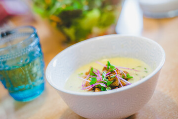Healthy and fresh homemade broccoli soup with croutons and radish sprouts, served in white ceramic bowl