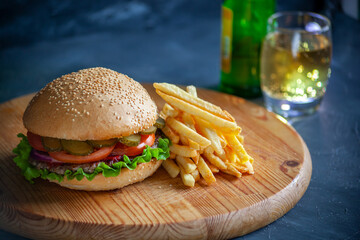 Hamburger with a knife lies on a board on a dark background
