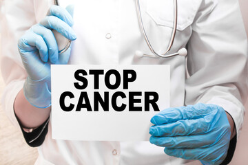 The doctor's blue - gloved hands show the word STOP CANCER - . a gloved hand on a white background. Medical concept. the medicine