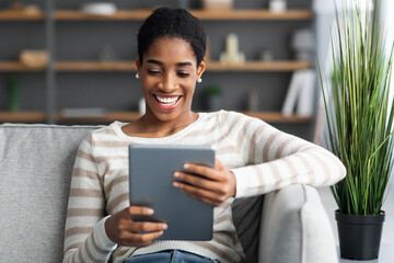 Smiling African American Woman Relaxing On Sofa With Digital Tablet At Home
