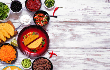 Taco bar side border with assorted ingredients. Top view on a rustic white wood background. Mexican...