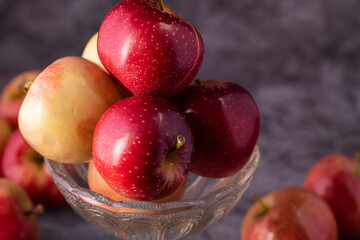 Fresh red and green apples in a glass vase close-up.