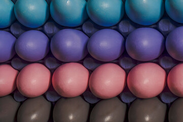 Close-up picture of painted multicolored Easter eggs forming pastel gradient lines, placed in a purple box. Stylish Easter conccept.