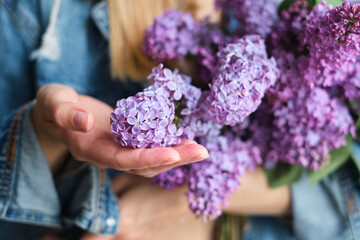 Happy woman holding bright purple lilac in her hands. Stylish lilac in the hand of the florist close up. Beautiful spring gentle flowers. Gift for the holiday. Fresh floral. Blossom petal