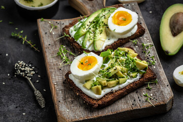 Toast with avocado and egg and soft cheese on Cereal Bread. Food recipe background. Close up. rustic wooden background
